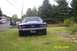 1967 Ford Mustang - A blue 1967 Ford Mustang is parked on a grassy lawn, with a dark SUV visible on the road in the background.
