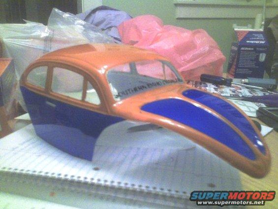 Orange and blue car body shell with text on windshield, resting on a notebook