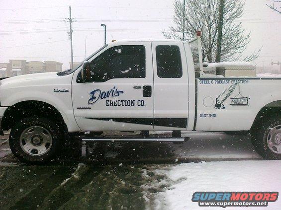 White Ford F-series pickup truck with "Davis ERECTION CO." and "STEEL & PRECAST ERECTION" graphics, parked in snow