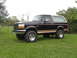 1994 Ford Bronco - This lifted Ford Bronco sits on a grassy lawn under an overcast sky.