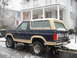 1985 Ford Bronco - Rear view of a 1985 Ford Bronco with a tan top parked on a snow-covered street.
