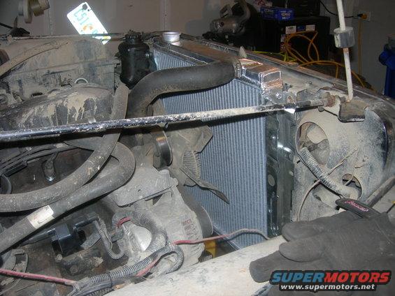 Engine bay showing a new radiator and fan assembly, with hoses and wiring visible