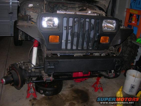1991 Jeep Wrangler front axle and suspension on jack stands, with front bumper and grille visible