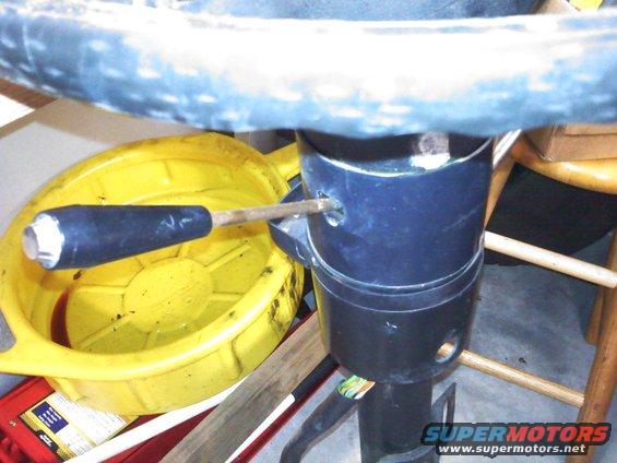 Steering column with turn signal lever extended, next to a yellow oil drain pan