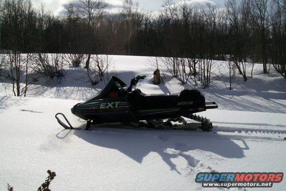 Side view of a black snowmobile with EXT lettering in green and white