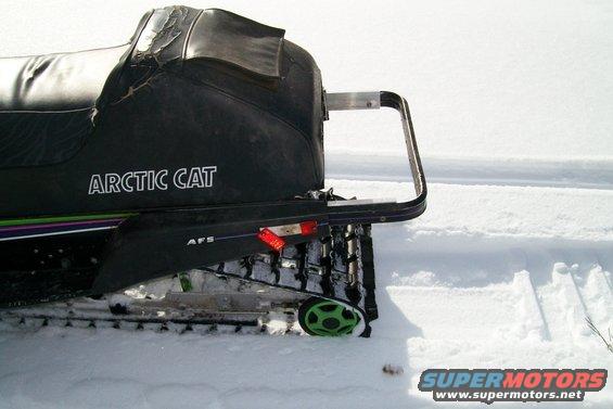 Rear view of an Arctic Cat snowmobile in the snow. Seat is torn