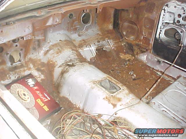 Interior of a car with extensive rust and exposed wiring. A McLeod clutch disc box is visible