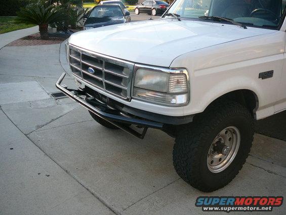 Front end of a white Ford F-Series truck with a chrome grille and aftermarket bumper