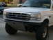 1988 Ford Bronco - Frontal view of a white Ford truck with a prominent chrome grille and a custom bumper.