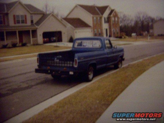 Right rear of the truck showing the tailgate net, sliding window, black bumper, and stance.