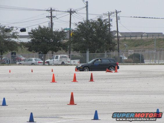 Dark station wagon driving around cones on a track
