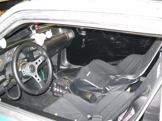 Interior view of a race car with racing seats, aftermarket steering wheel, and custom dashboard gauges