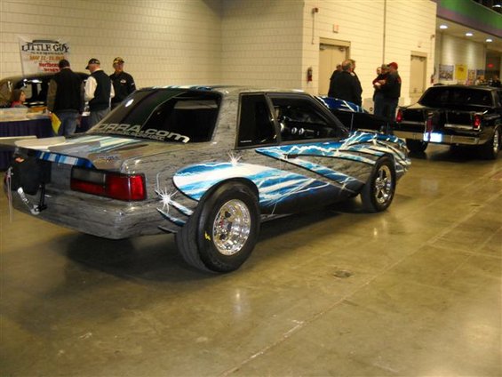 Customized 1992 Ford Mustang drag car with lightning graphics, rear view. Another car is visible behind it