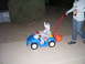 1991 Ford Bronco - A child dressed in a costume rides in a toy car, pulled by an adult holding a beverage.