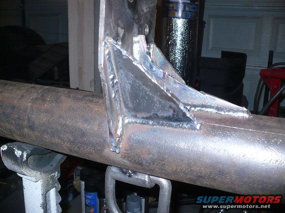 Welded metal brackets on a pipe, part of a vehicle frame