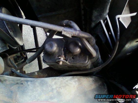 Close-up of a black engine part with hoses attached