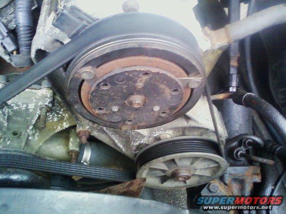 Close-up of engine belt and pulleys, showing wear and rust