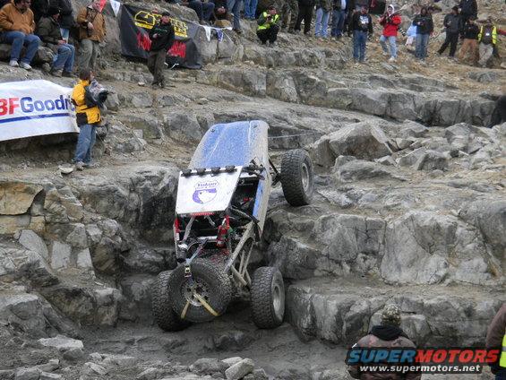 Off-road buggy with blue top climbing a rocky incline, BFGoodrich banner visible