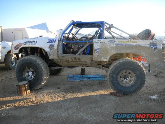 Modified off-road truck with roll cage, number 301, and Goodyear tires. Another vehicle is partially visible to the left