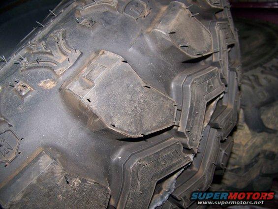 Close-up of aggressive off-road tire tread pattern with visible sidewall details