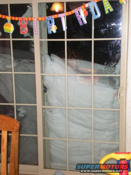 Snowdrift piled high against a sliding glass door with a birthday banner