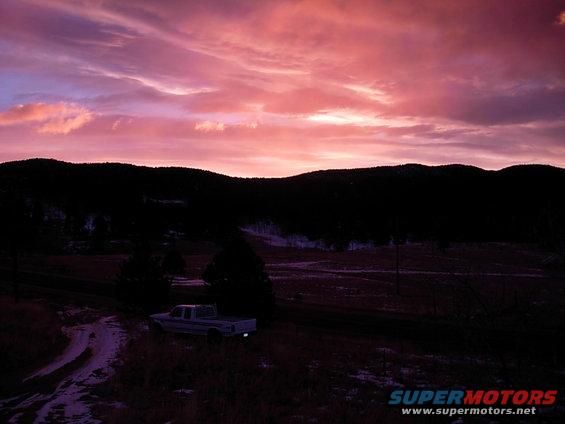 Pickup truck parked on a dirt road with a colorful sunset sky
