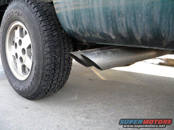 Dual exhaust pipes on a green truck with Firestone Destination A/T tires