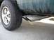 1995 GMC Sierra 1500 - Close-up of the dual exhaust pipes and rear tire of a green truck, showing Firestone Destination A/T tires.