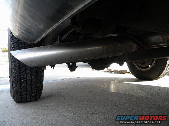 Underside view of a truck's exhaust pipe and rear tire