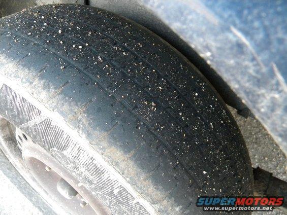 Close-up of a worn tire with gravel embedded in the tread