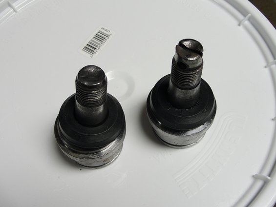Two metal ball joints with rubber boots on a white surface