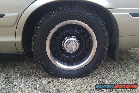 Close-up of a car's wheel and tire with a Mercury logo on the hubcap
