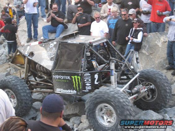 Off-road buggy with large tires and Monster Energy logos navigating rocky terrain, number 2 visible