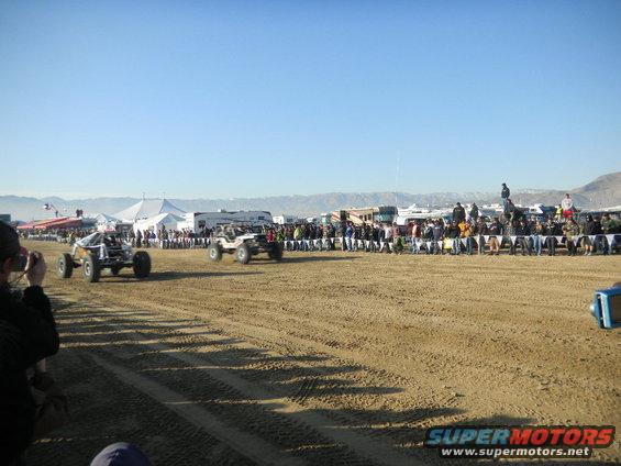 Off-road race vehicles on dirt track with spectators