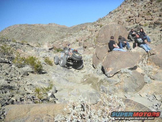 Off-road buggy with spare tire on back navigates rocky terrain