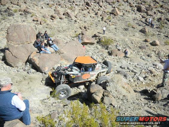 Off-road buggy with orange roof and number 435 on side, navigating rocky terrain