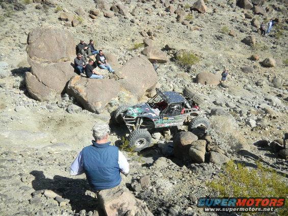 Off-road buggy with custom bodywork navigating a rocky, desert terrain