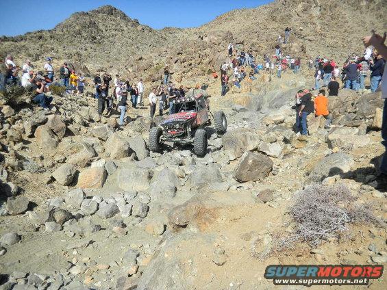 Off-road buggy climbing rocks with spectators watching