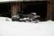 1990 Arctic Cat El Tigre EXT - Snowmobile sits in deep snow near a rustic wooden building.
