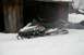 1990 Arctic Cat El Tigre EXT - A black 1990 Arctic Cat El Tigre EXT snowmobile sits partially buried in snow next to a weathered wooden building.