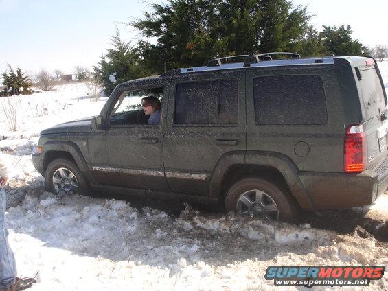 Dark green Jeep Commander stuck in snow, side view