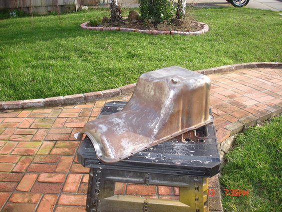 Old oil pan sitting on a black sawhorse outdoors