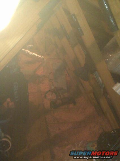Attic scene with insulation, wooden beams, and a bicycle