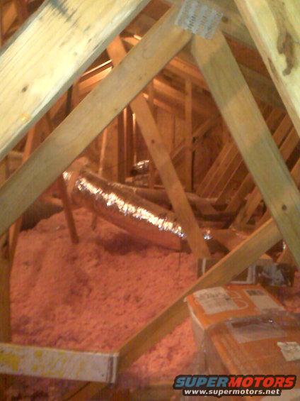 attic space with pink insulation and a silver duct running through it