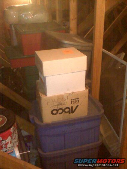 Cardboard boxes stacked in an attic, one with 'BROGI' and 'ABCO' written on it