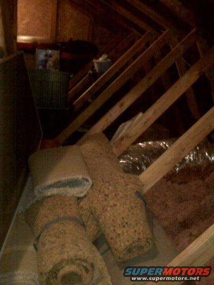 Attic scene with rolls of insulation and wooden beams