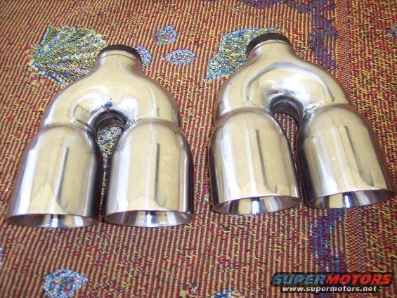 Pair of chrome quad exhaust mufflers with black tips, angled view