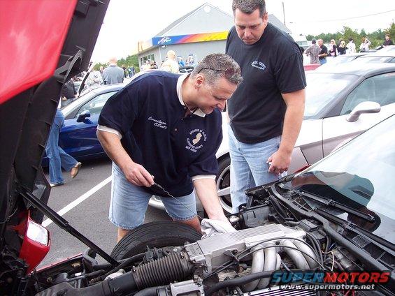 Red car engine bay with two men inspecting it