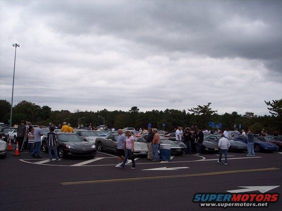 Several Chevrolet Corvettes parked in a lot under a cloudy sky