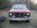 1985 Ford Bronco - Front view of a red truck with a missing grille and aftermarket lights, a "FOX" sticker on the windshield.